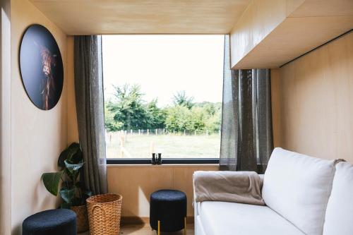 a living room with a couch and a window at Tiny House in the Nature of Bruges in Beernem