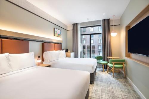 a hotel room with two beds and a flat screen tv at Holiday Inn Melbourne Bourke Street Mall by IHG in Melbourne