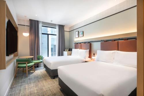 a hotel room with two beds and a tv at Holiday Inn Melbourne Bourke Street Mall by IHG in Melbourne