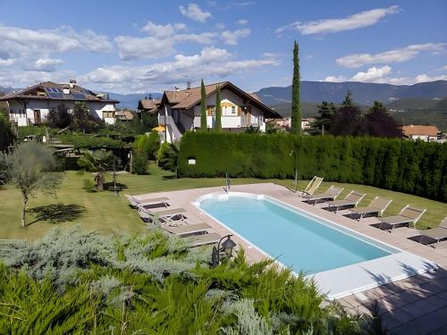 a swimming pool in a yard with chairs and a house at Stompferhof Familienapartment in Caldaro