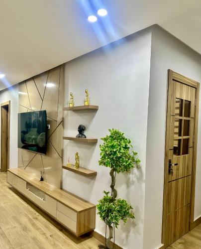 a living room with a tv and a plant on a wall at Lush Cove Apartments in Lekki