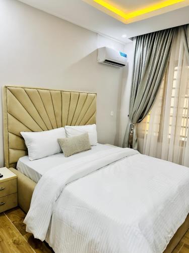 a bedroom with a bed with white sheets and a window at Lush Cove Apartments in Lekki