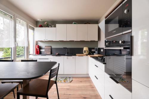 a kitchen with white cabinets and a table with chairs at Gîte De L'enclume in Sévignac