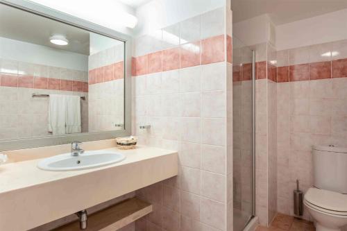 a bathroom with a sink and a toilet and a mirror at Royal Islander Club Resort La Terrasse in Lowlands