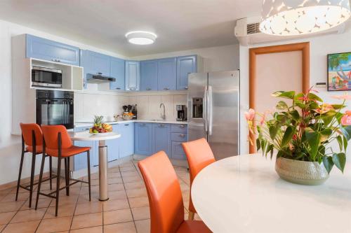 a kitchen with blue cabinets and a white table with orange chairs at Royal Islander Club Resort La Terrasse in Lowlands