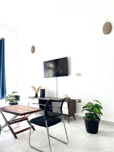 a table and a chair in a room with a tv at Cosy central apartment in Makindi