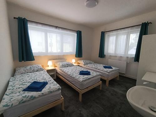 two beds in a room with a sink and two windows at Apartmány Beseda in Jablonec nad Nisou