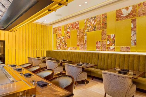 a restaurant with yellow walls and wooden tables and chairs at InterContinental Hotels Jakarta Pondok Indah by IHG in Jakarta