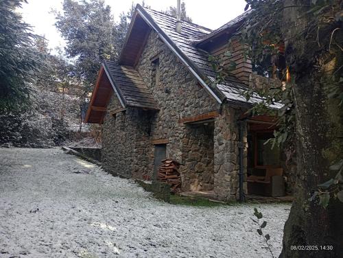 an old stone house sitting on top of a field at LA Nevadita, Chalet cabin located near the center- It includes suite room with double bed and another 2 bedrooms with two singles beds- Living room fireplace, Hot water, WI-FI in Villa La Angostura