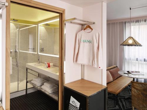 a bathroom with a sink and a white shirt on a mirror at Mama Shelter Paris West in Paris