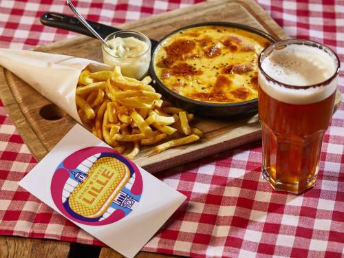 a tray of food with a bowl of fries and a glass of beer at Mama Shelter Lille in Lille
