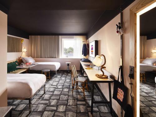 a hotel room with two beds and a table and chairs at Mama Shelter London - Shoreditch in London