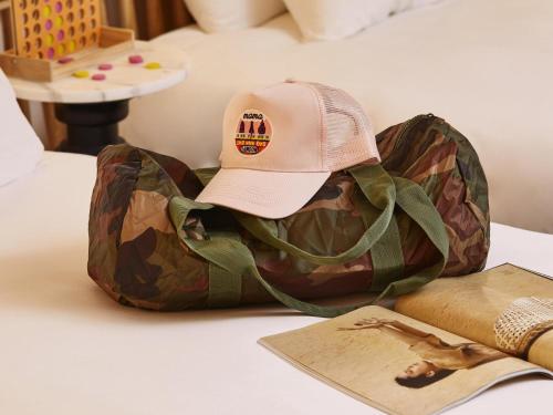 a hat sitting on top of a bag on a bed at Mama Shelter London - Shoreditch in London