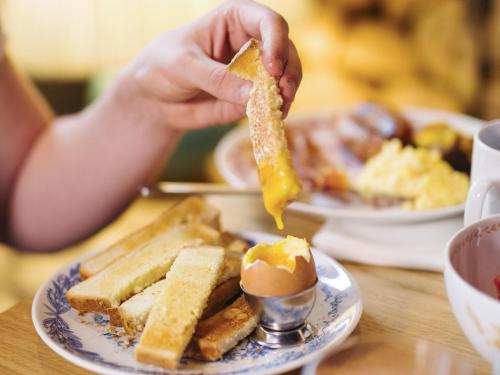 a person holding a piece of toast with peanut butter and eggs at Mama Shelter London - Shoreditch in London