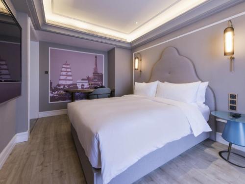 a bedroom with a large white bed and a table at Mercure Xi'an Downtown in Xi'an