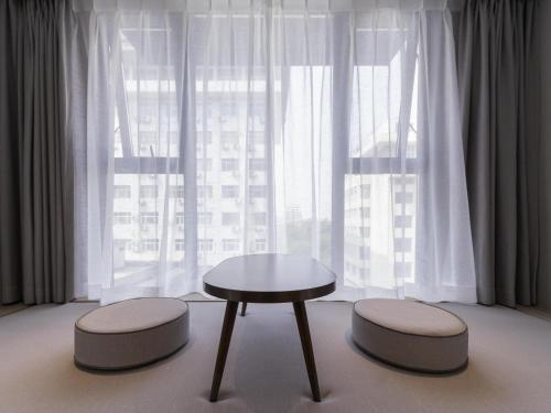 a table and two stools in front of a window at Mercure Xi'an Downtown in Xi'an