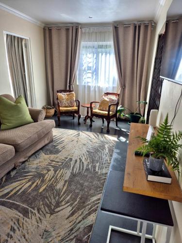 a living room with a couch and chairs and a table at Fortune Cottage in Cape Town