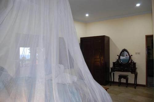 a bedroom with a white veil and a mirror at Beachfront Villa Jepun Segara in Banjar