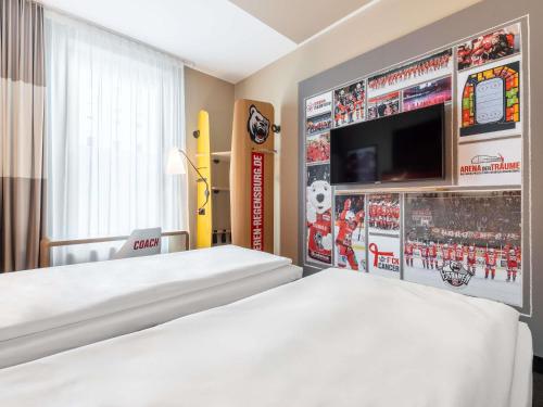 a hotel room with a bed and a flat screen tv at ibis Regensburg Zentrum in Regensburg
