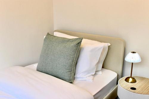 a bed with a green pillow and a side table at Stockport Stays in Stockport