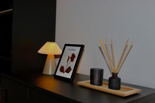 a table with a picture and a lamp and some sticks at Stockport Stays in Stockport