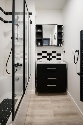a bathroom with a black vanity and a shower at Le Casa Délia in Équemauville