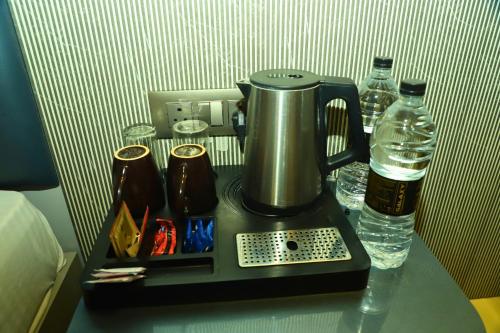 a coffee maker on a table with a bottle of water at Hotel Shirdi Park Inn 80 Meters From Sai Samadhi Temple in Shirdi