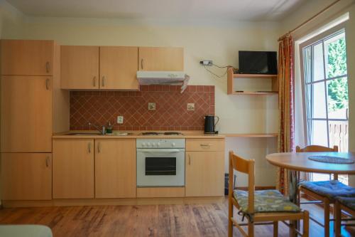 a kitchen with wooden cabinets and a table with chairs at Apartmány Lékařský dům in Pec pod Sněžkou