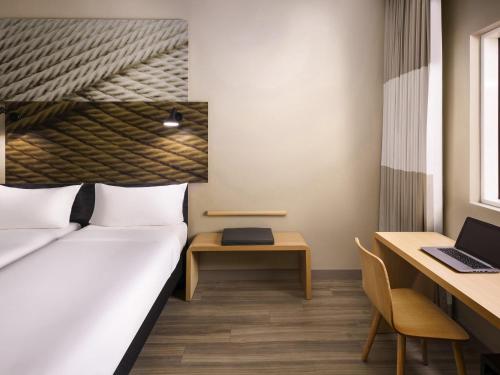 a bedroom with a bed and a desk and a laptop at Ibis Jeddah Malik Road in Jeddah