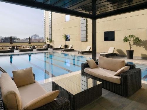 a swimming pool with couches and chairs in a building at Ibis Jeddah Malik Road in Jeddah