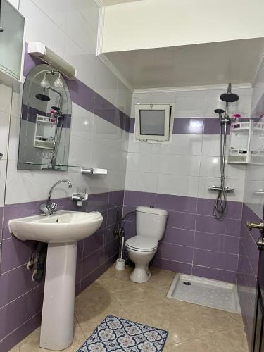 Baño blanco y púrpura con aseo y lavabo en Réservez dès maintenant Calme confort et proximité, en Oulad Mbark