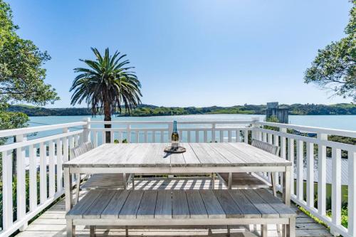 a picnic table on a deck with a view of the water at Harbour Rose House in Raglan