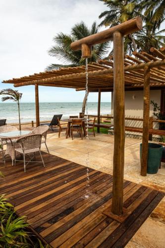 a wooden deck with a umbrella and a table and chairs at Vila Picos Icapui in Icapuí
