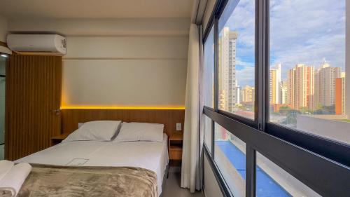 a hotel room with a bed and a large window at Flat - Setor Bueno T-63 - Lindo e Aconchegante in Goiânia