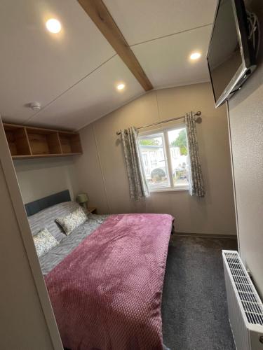 a small bedroom with a bed and a window at The Orchards modern caravan in Saint Osyth