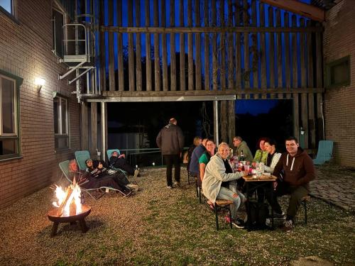 a group of people sitting around a table next to a fire at Sporthotel Streitberg in Streitberg