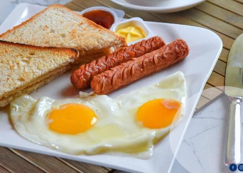 a plate of breakfast food with eggs sausage and toast at Portia beach grand 2 in Male City