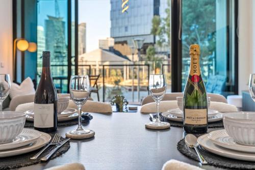 a table with two bottles of wine and glasses at Luxe 3BR CBD Apartment with River Views and Resort Style Amenities in Melbourne