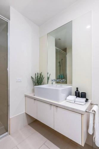 a white bathroom with a sink and a mirror at Luxe 3BR CBD Apartment with River Views and Resort Style Amenities in Melbourne