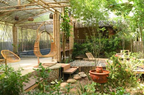 a patio with chairs and a swing in a garden at Dinh Gia Trang - Homestay & Coffee in Yên Bái