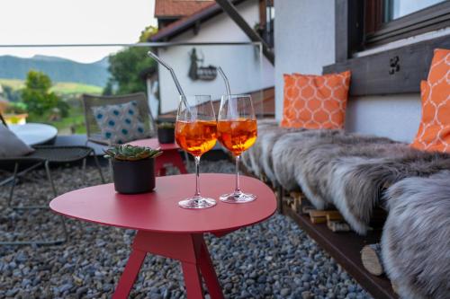 two wine glasses sitting on a red table on a patio at DIANA Naturpark Hotel - Partnerbetrieb von "Oberstaufen PLUS GOLF" in Oberstaufen