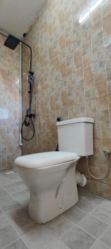a toilet in a bathroom with a shower at 1 minute walk to Victoria Mall in Entebbe