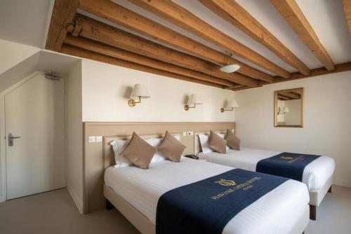 zwei Betten in einem Zimmer mit Holzdecke in der Unterkunft Hotel Havane Opera in Paris