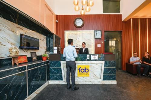 a man standing at a reception desk in a lobby at FabHotel Black Stone Palace in Ghaziabad