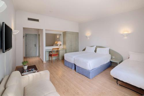 a hotel room with two beds and a couch at NH Ancona in Ancona