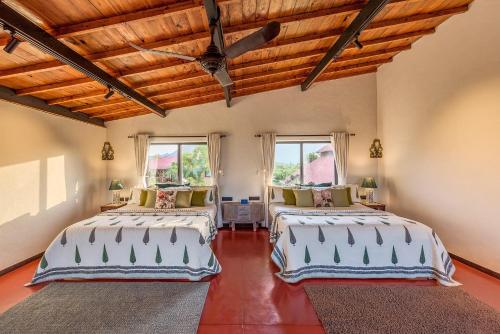 two beds in a room with two windows at SaffronStays Satori Hornbill, Ultra Luxe two bedroom Villa on 8 Acres Estate, By The Mulshi Lake in Mulshi