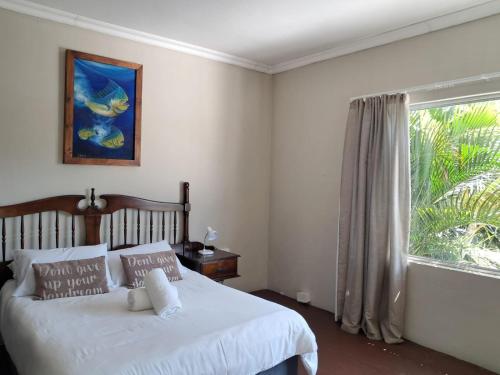 a bedroom with a white bed and a window at SeaXplore Lodge & Dive Center in Sodwana Bay