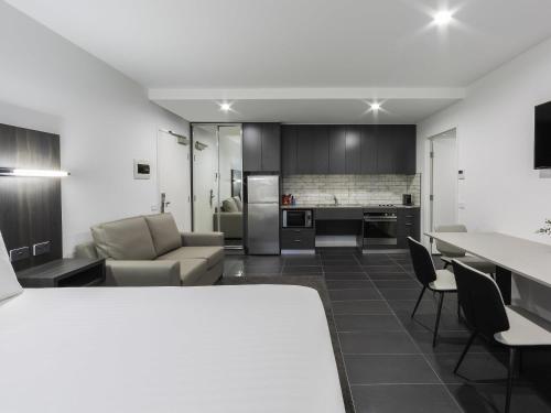 a living room with a couch and a kitchen at The Sebel Canberra Civic in Canberra