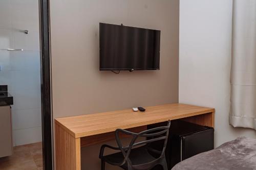 a room with a desk with a television on a wall at Sttudio One in Araxá