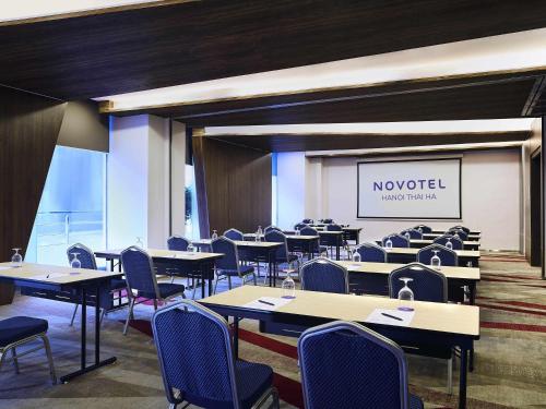 a dining room with tables and chairs and a screen at Novotel Hanoi Thai Ha in Hanoi